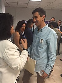 A smiling, casually-dressed Pedro Kumamoto speaks to a woman