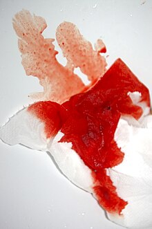 Pezzo di carta igienica con sangue mestruale dai colori vivaci.