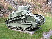 tracked green-painted tank with turret mounted on a concrete slab