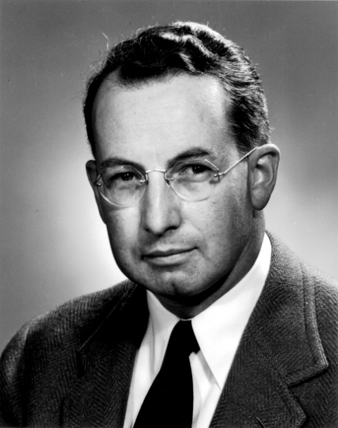Head and shoulders of a man in suit and tie with glasses