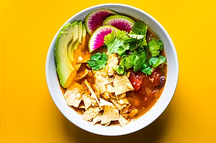 A bowl of tortilla soup with all of the garnishes