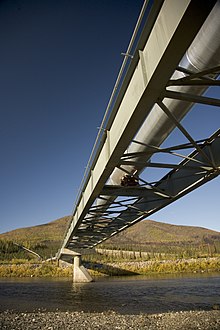 Photo d'un pont traversant un cours d'eau, sur lequel est installé l'oléoduc.