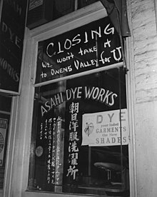 A Japanese American shop, Asahi Dye Works, closing. The notice on the front is a reference to Owens Valley being the first and one of the largest Japanese American detention centers. WWII - Shop just before Japanese were evacuated from Little Tokyo, Los Angeles, California, by Clem Albers, April 1942.jpg