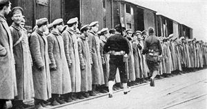 Yhdysvaltalainen matruusi ja jalkaväkisotilas vahvuustarkastavat 123 ranskalaisia vastaan taistellutta neuvostovenäläistä sotavankia 6.7.1918 Arkangelin lähellä olevalla asemalla.
