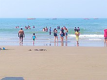 Tourists at Vagator beach in Goa. Ships can be seen in the background. Boys and girls at Goa beach.jpg