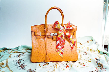Hermès Ostrich Birkin bag, with matching leather-covered lock and key lanyard, displayed with a plaid bow