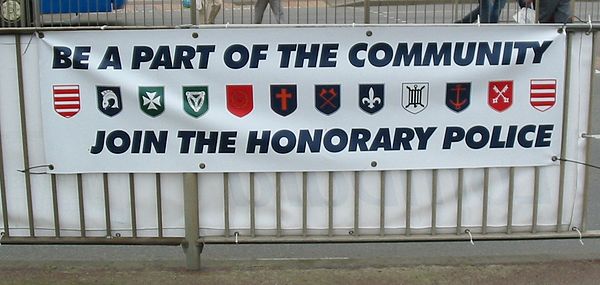 A recruiting banner for the Honorary Police showing the arms of each parish: (from left to right) Grouville, St Brelade, St John, Trinity, St Saviour,