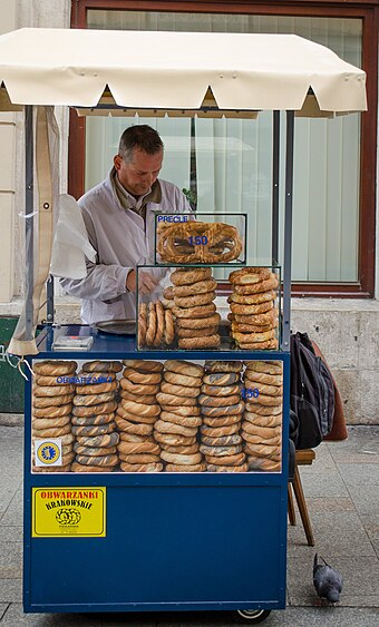 A street vendor in Kraków selling obwarzanki and pretzels from a typical cart