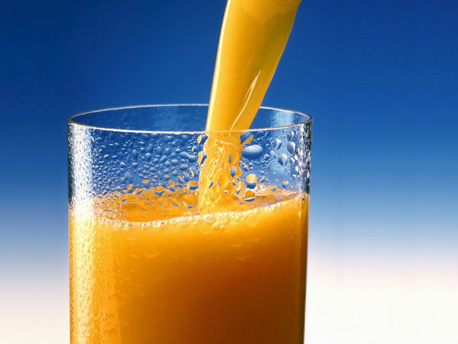 Стакан апельсинового сока в руке