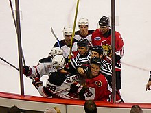 Comrie (right foreground) with the Ottawa Senators, fighting with Brian Rafalski as referees attempt to break it up Senators vs Devils Jan 6 2007.jpg