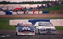 Irvine driving the SCB Vehicle Dismantlers Peugeot 405 at Silverstone during the 1995 British Touring Car Championship season. Tim Harvey - Volvo 850 20v tries the outside line on Hamish Irvine - Peugeot 405 Mi16 at the British GP support round of the BTCC 1995 (49773138332).jpg