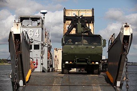 U.S. Marines from Combat Logistics Battalion 8 and Navy personnel from Beach Master Unit 2 off-load ISO containers from a Landing Craft Utility with a Logistics Vehicle System Replacement