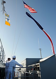 US Navy 120123-N-BK435-007 Sailors assigned to the submarine tender USS Frank Cable (AS 40) raise the Ensign and the 165-foot Homeward Bound Pennan.jpg