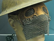 a mask with a leather upper with slits on the metal eyepieces, and a chain mail lower, modelled on a dummy head with a metal war helmet