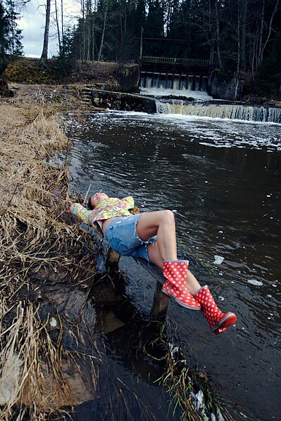 File:Woman with flowered shirt shorts and red boots near a river.jpg