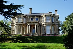 A photograph showing the 19th century bath stone manor house, overlooking the city of Newport and surrounded by the green spaces of the Park