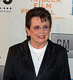 A brown haired women in a black jacket and white shirt