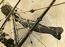 The Australian flag is hoisted as a battle ensign on HMAS Hobart during the invasion of Guadalcanal during World War II. HMAS Hobart.jpg