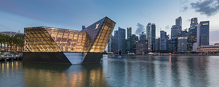Bâtiment polyédrique éclairé Louis Vuitton au-dessus de l'eau à Marina Bay le soir, avec des gratte-ciel du Central Business District en arrière plan, Singapour. Juin 2018.