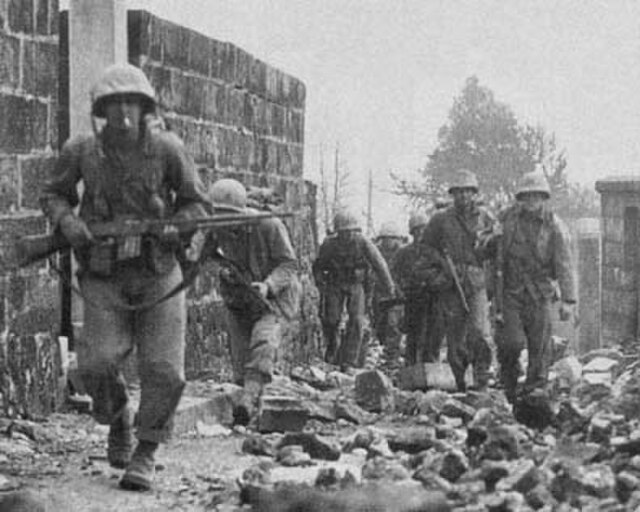 A patrol of Marines from the 6th Marine Division searches the ruins of Naha, Okinawa in April 1945.