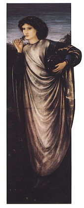 Une femme brune debout, portant une longue robe et tenant une petite branche dans sa main qu'elle porte à sa bouche.