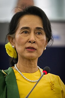 Aung San Suu Kyi standing before a microphone