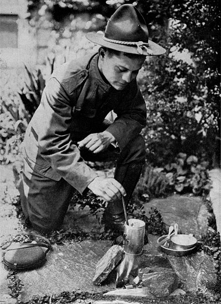 An American soldier boiling his rations using rolls of silk to create a cooking fire without smoke, 1917