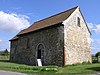 Une église en pierre aux allures de grange très simple avec un toit de tuiles