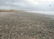 A beach of sand pebbles in Tyrella. You can see the ocean in the background.