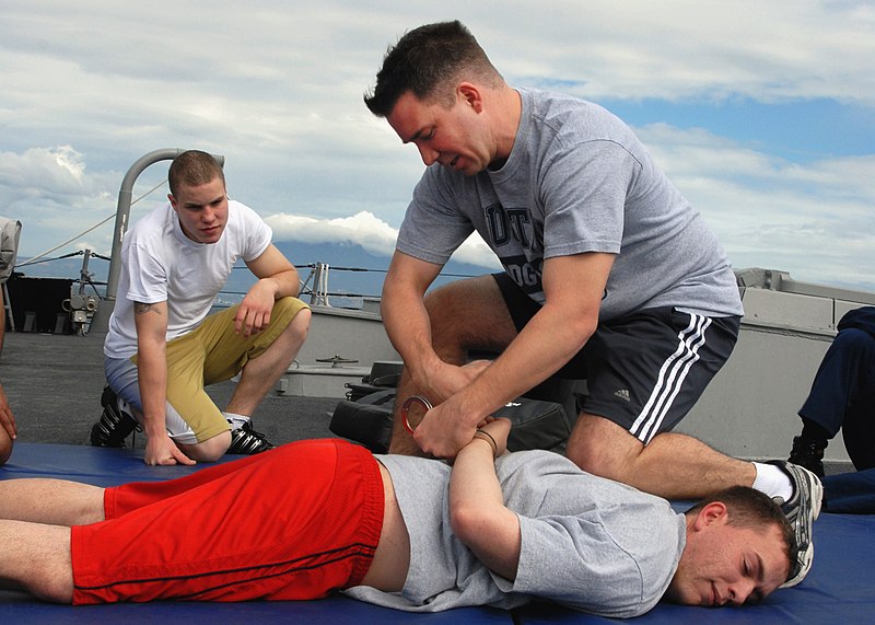 File:US Navy 080219-N-7446H-004 Operations Specialist Seaman Michael Leek watches as Chief Master-at-Arm's Christopher Crane handcuffs Fire Controlman 1st Class Paul Rohlinger.jpg