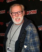 Photo en couleur d'un homme, Jay Lynch, avec une barbe blanche et des lunettes.