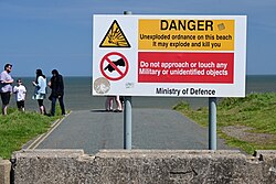 A sign warning of unexploded military ordinance at the Aldbrough Cliff, an area of coastal erosion in the East Riding of Yorkshire.