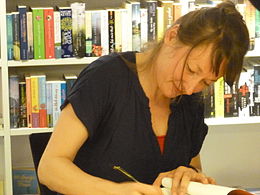 Foto einer jungen weißen Frau mit langen braunen Haaren, die sich über ein Buch beugt, in Widmung