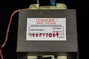 A transformer from a microwave oven, featuring a prominent warning of the danger of high voltage. Caso SMG20 - MD Microwave Oven Manufacturing MD-801EMR-1-0189.jpg