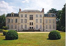 Photographie en couleurs d'un château, constitué de trois corps de bâtiments, chacun de deux étages, le toit étant en ardoises ; une pelouse au premier plan.