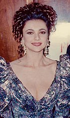 White woman with brown curly hair wearing a blue dress smiling at the 62nd Academy Awards.