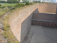 Counterscarp of a Napoleon era polygonal fort (Fort Napoleon, Ostend). Counterscarps had become vertical by this time. The housing at the bottom of the ditch is a caponier from where the defenders could fire on attackers that managed to climb down into the ditch, while being protected from cannon fire themselves. FortN.gracht03.jpg