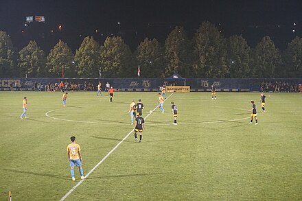 A kick off. Players other than the kicker are required to be in their team's own half of the pitch and opposion players may not be in the 10-yard diameter centre circle. Milwaukee vs. Marquette men's soccer 2022 12 (kick-off).jpg