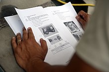 A technician referring to an instructional handbook for the operation of a machine New Horizons Medical Support in Trujillo 150612-F-LP903-148.jpg