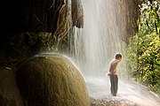 un jeune garçon sous une cascade d'eau fraîche