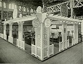 Un stand d'exposition à l'intérieur duquel on voit des meubles-vitrines et des lampes tout autour.