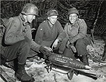 A 155mm shell used in WWII with inscription. Three gunners from Battery C, 28th Field Artillery Battalion, 8th Infantry Division, prepare to fire a 155mm shell with inscription.jpg