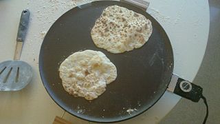 Two lefse cooking on a Heritage grill, nearly ready to be served.