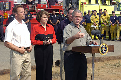 With Schwarzenegger and Senator Dianne Feinstein behind him, President George W. Bush comments on wildfires and firefighting efforts in California, October 2007.