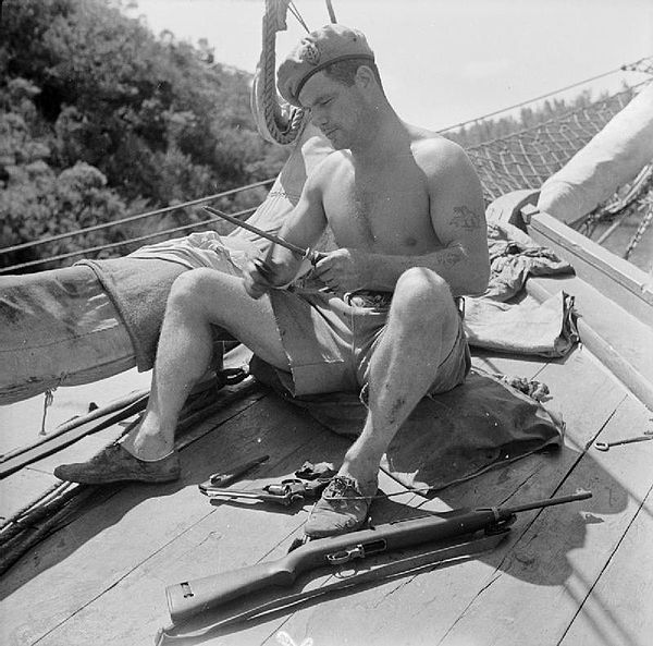 Corporal Aubrey sharpens his fighting knife as he prepares for combat in the Aegean Sea in 1944