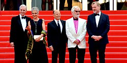 A picture showing five people standing on a red carpet