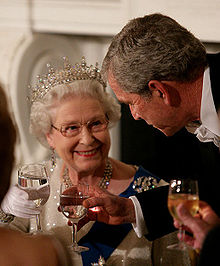 In evening wear, Elizabeth and President Bush hold wine glasses of water and smile