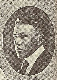 A black-and-white photograph. Enclosed in an oval, the face of a young man in a suit and tie faces leftward.
