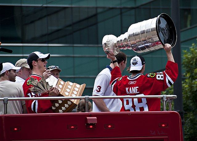 Patrick Kane hoisting the Stanley Cup and Jonathan Toews holding the Conn Smythe Playoff MVP Trophy, during the Blackhawks' parade and rally.