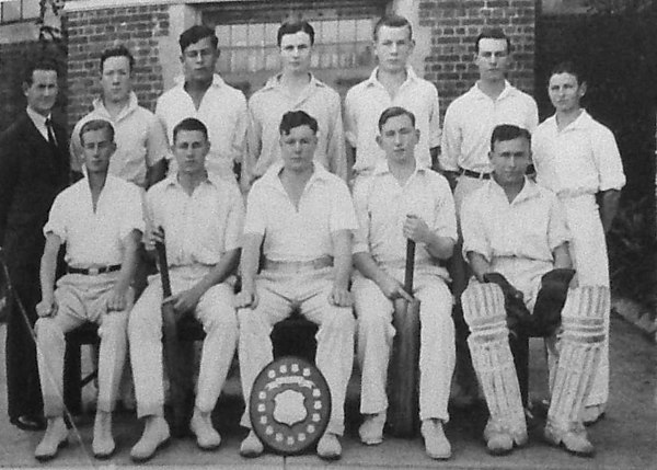 The Melbourne High School cricket team. Miller is standing at right. Truscott is seated with shield.